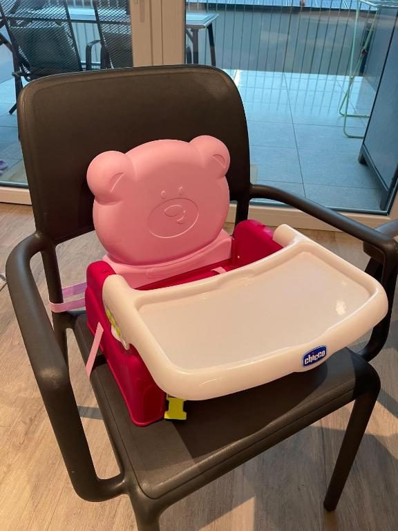 High chair booster seat with tray on a chair by the terrace window