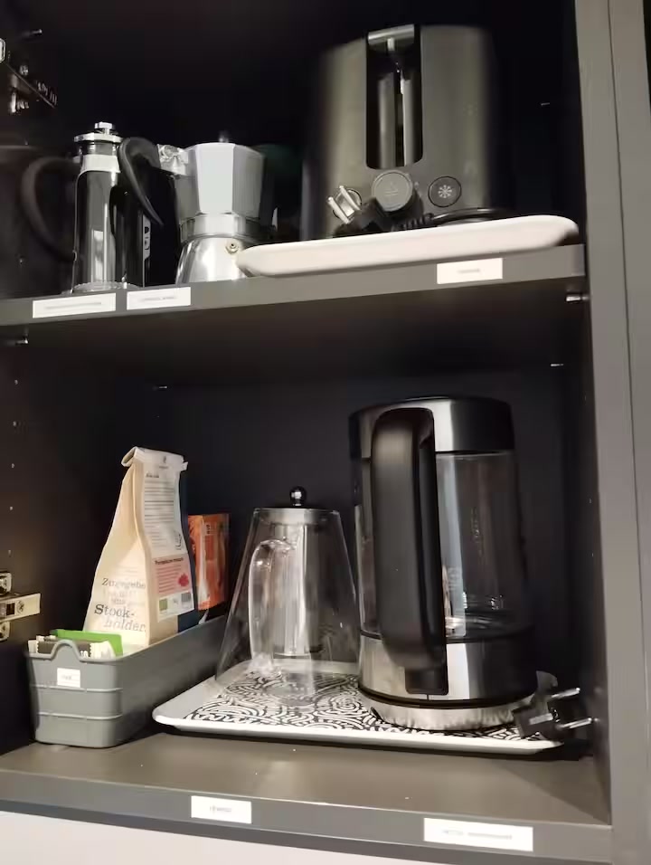 Labelled shelves with French press, moka pot, toaster, kettle and tea