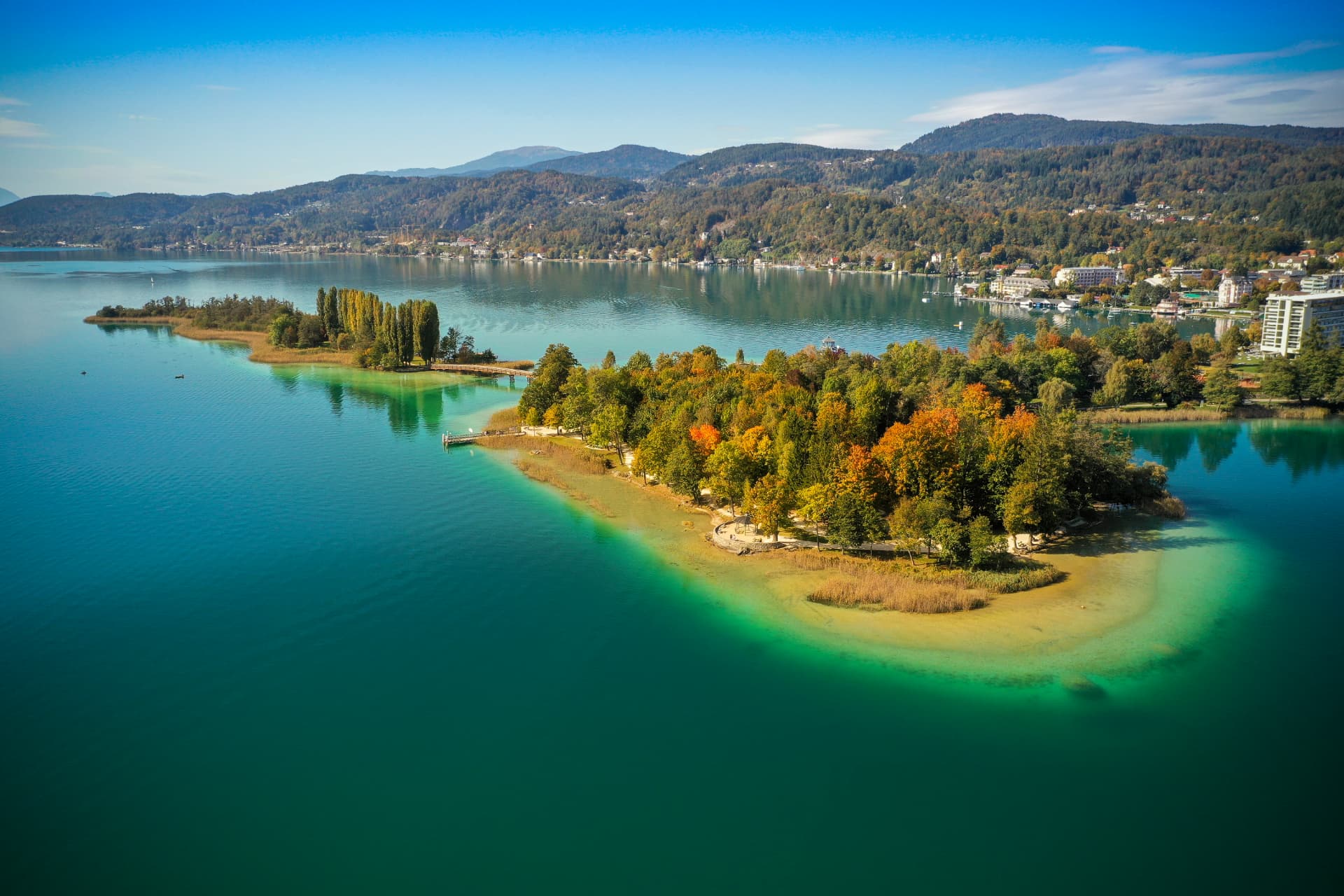 Aerial view of the Wörthersee shoreline with autumn colours and turquoise water