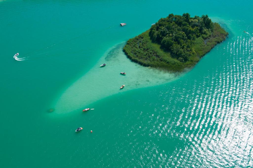 Aerial view of a small wooded island with moored boats in glittering turquoise water