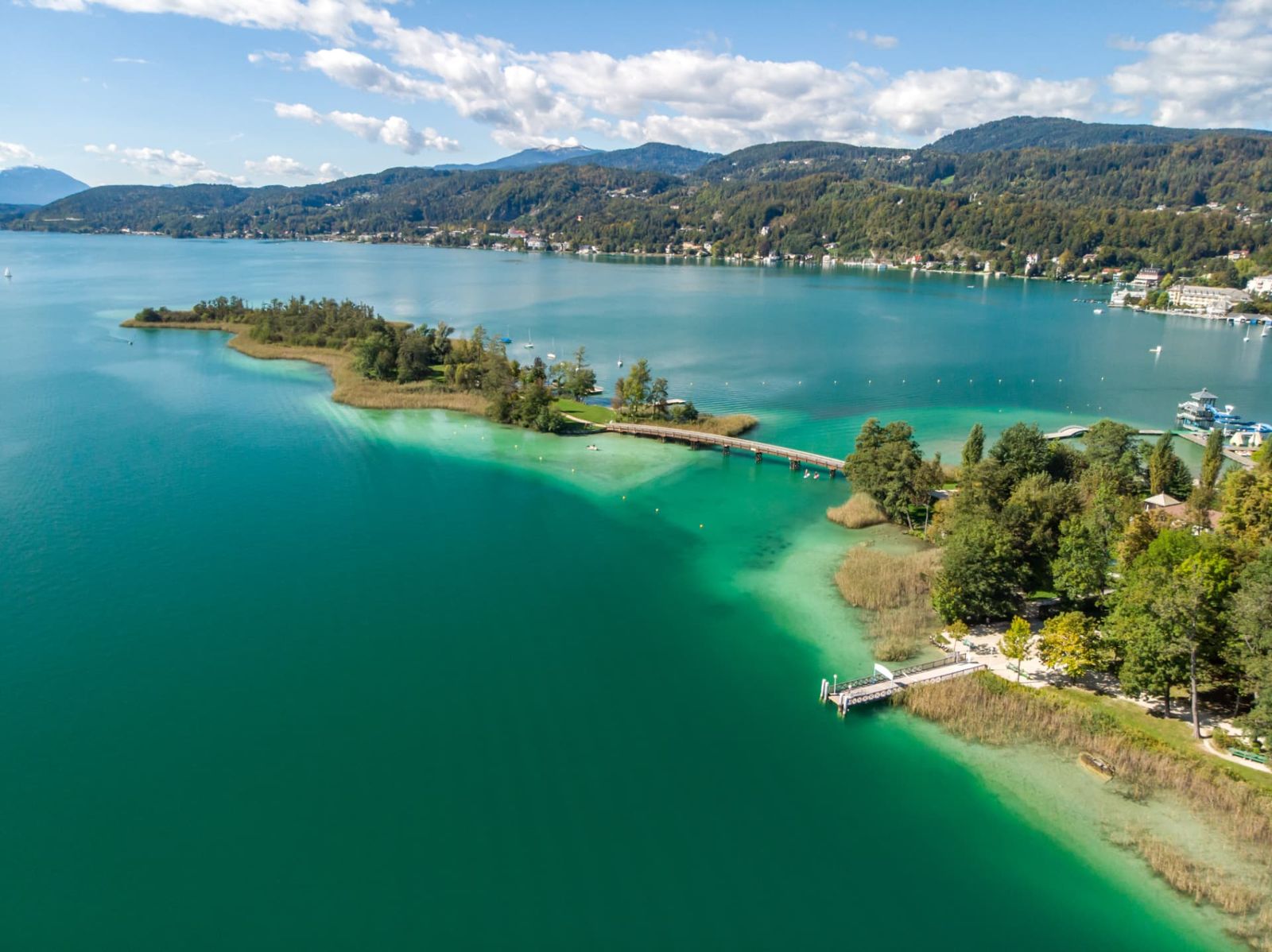 Wooded peninsula with a wooden footbridge and jetties reaching into turquoise water
