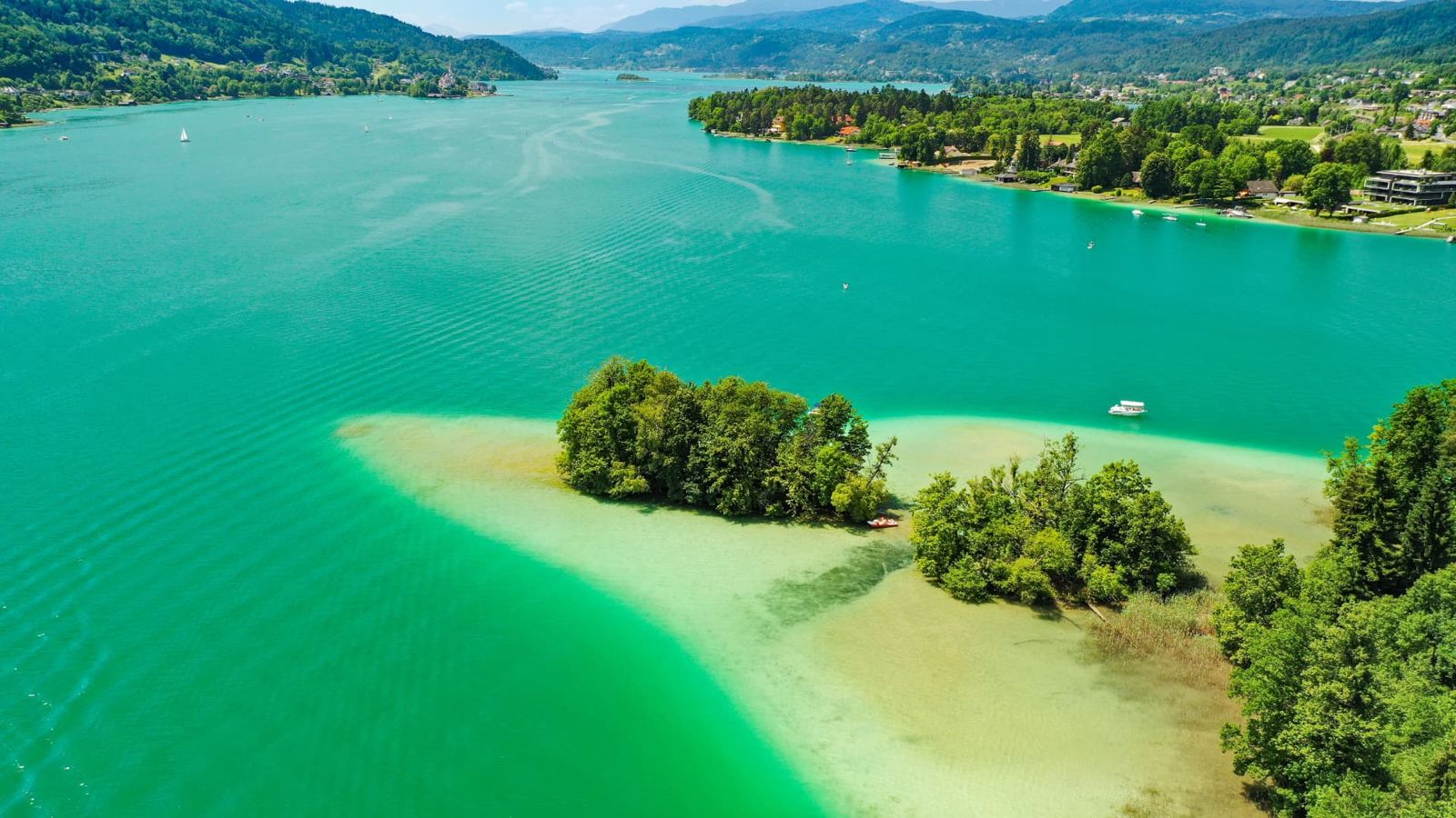 Aerial view of turquoise shallows and small wooded islets on Lake Wörthersee